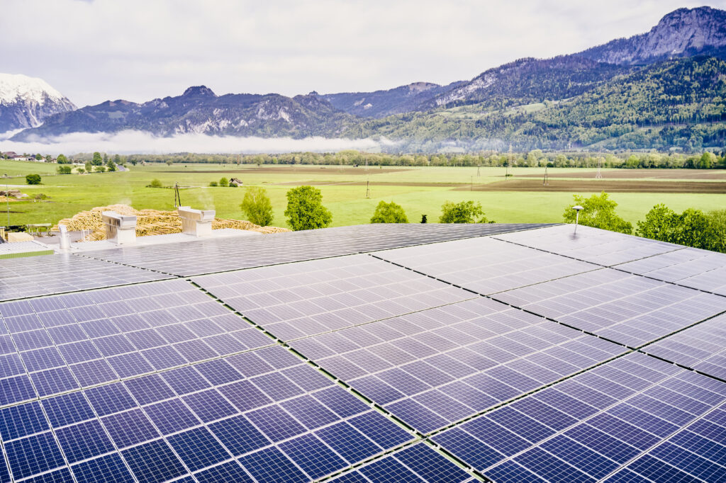 Photovoltaikanlage fotografiert von oben, vor einer Berglandschaft