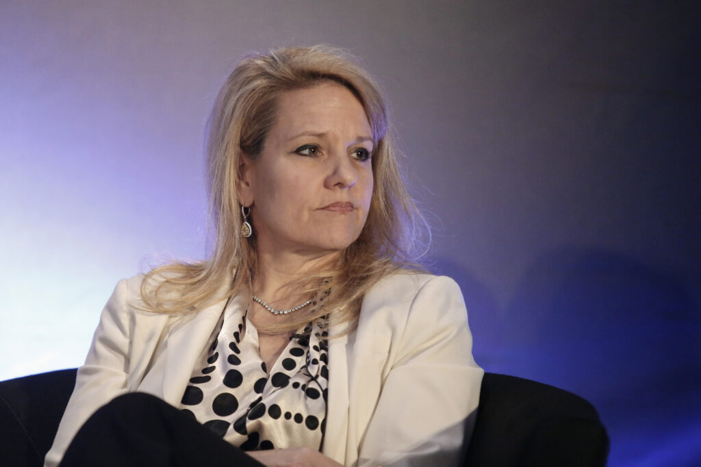 Gwynne Shotwell trägt einen hellen Blazer und blickt seitlich an der Kamera vorbei