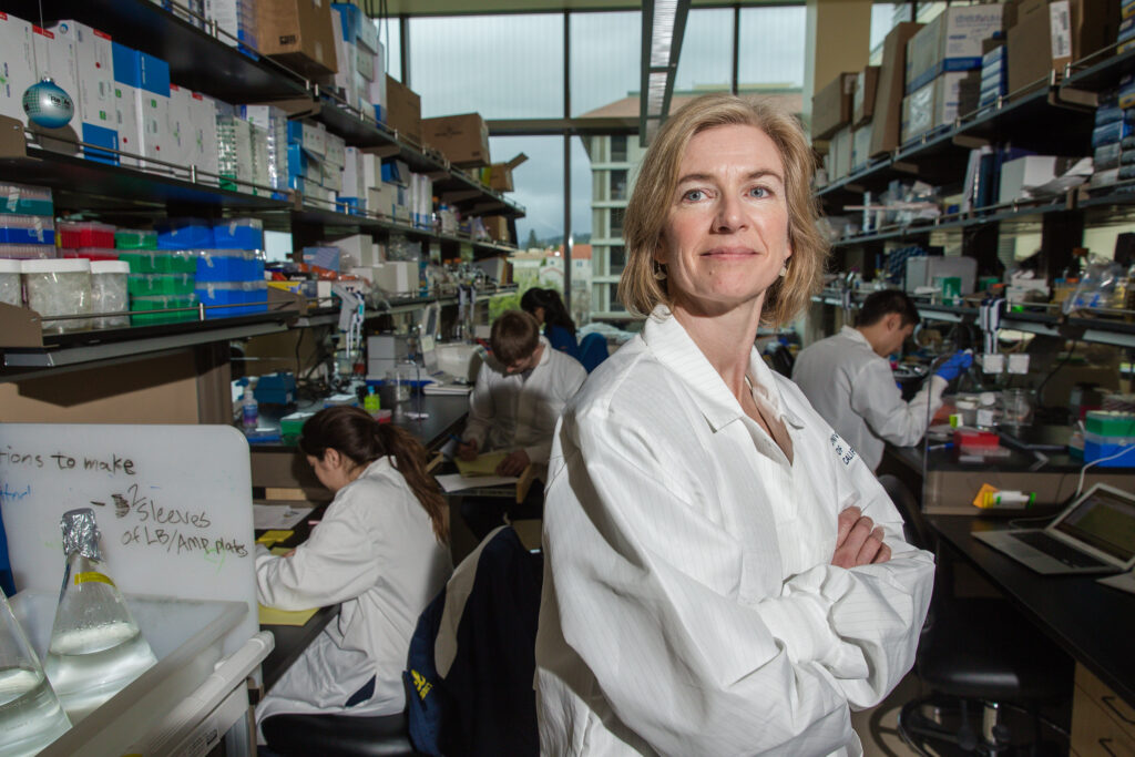 Jennifer Doudna mit einem weißen Labormantel in einem riesigen Labor