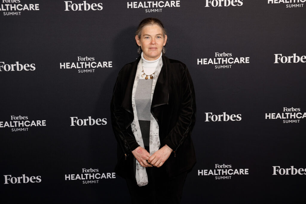 Daphne Koller steht auf der Bühne beim Forbes Healthcare Summit und lächelt in die Kamera