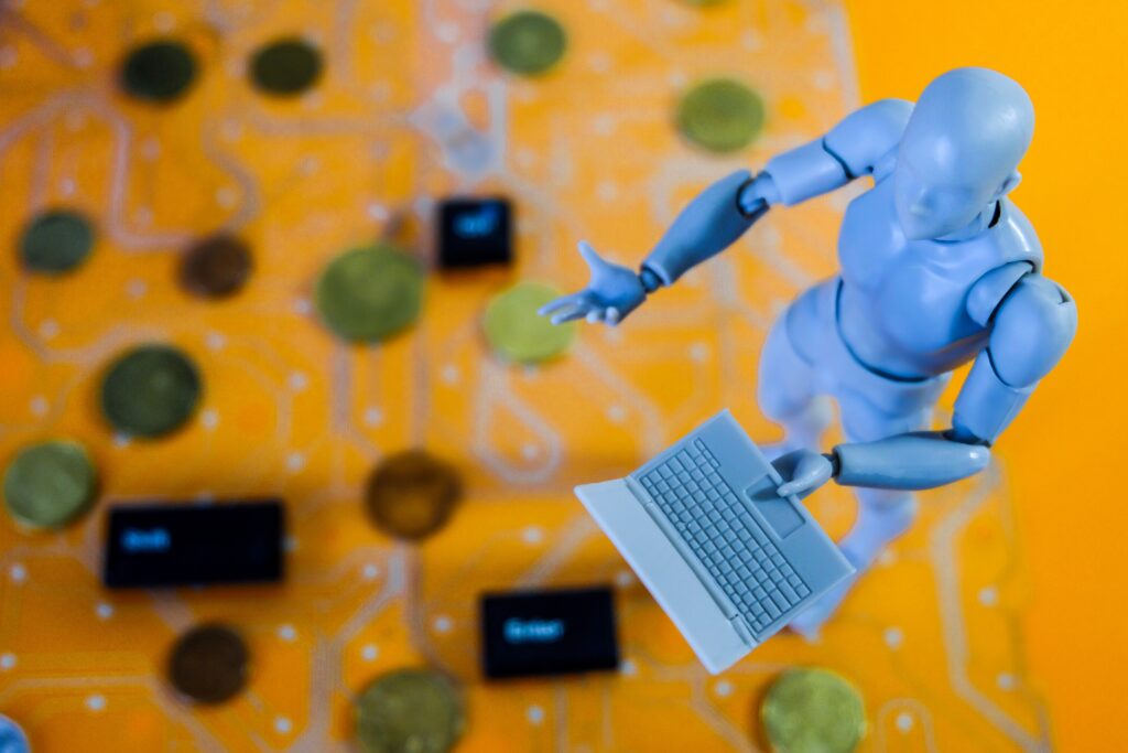 Gelber Hintergrund. Davor auf der rechten Seite eine kleine männliche Spielfigur in grau die einen Computer hält