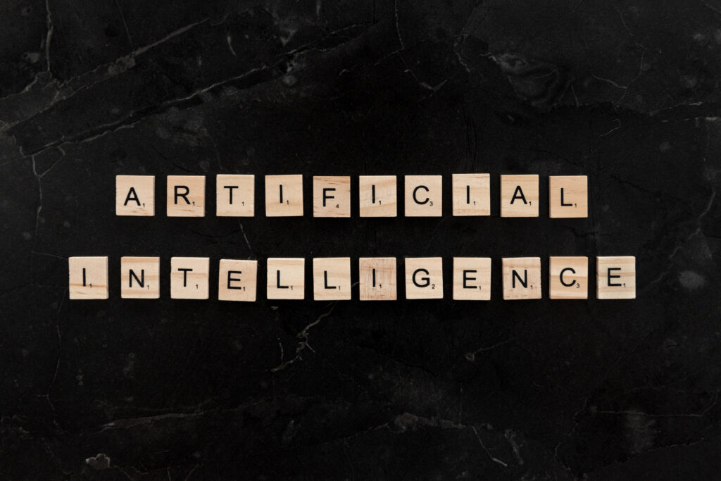 schwarzer marmorierter Hintergrund auf dem Holzbuchstaben zu sehen sind mit denen das Wort Artificial Intelligence geschrieben ist