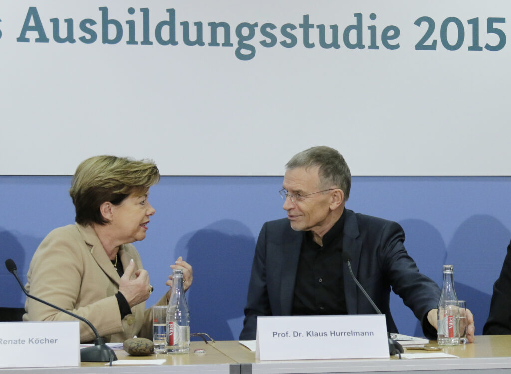 Klaus Hurrelmann sitzt auf einem Podium neben einer Frau die er ansieht; dahinter steht Ausbildungsstudie 2015
