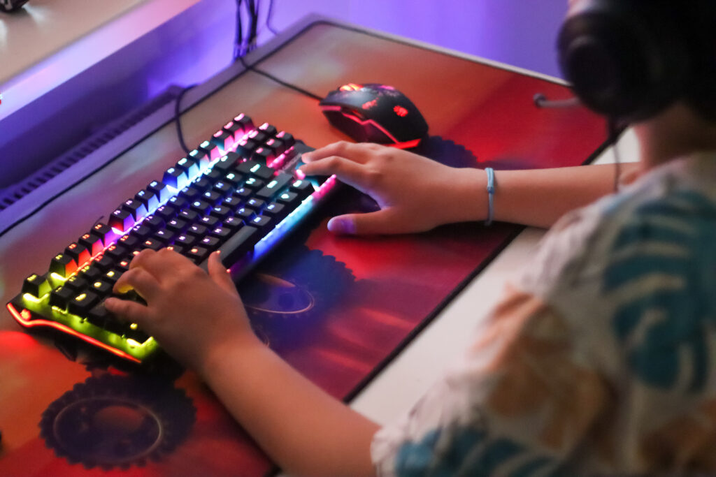Beleuchtete Computertastatur und die Hände von einem Teenager