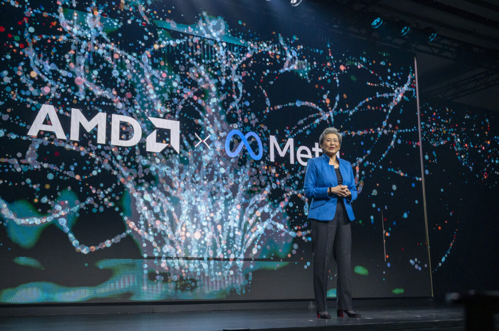 Lisa Su auf der Bühne mit blauem Sakko und schwarzer Hose. Dahinter das Logo von AMD und Meta