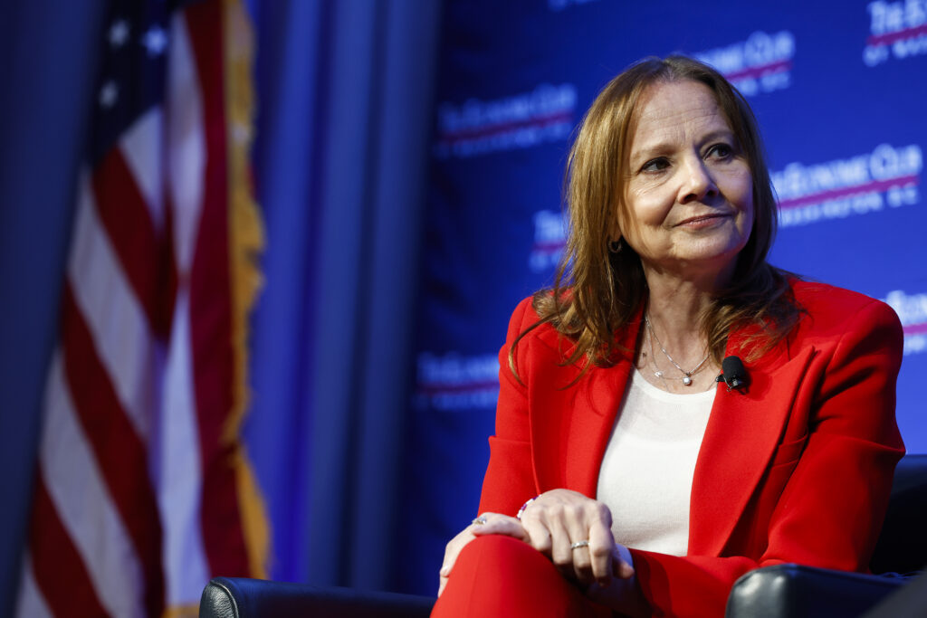 Mary Barra mit roten Hosenanzug sitzt auf einer Bühne