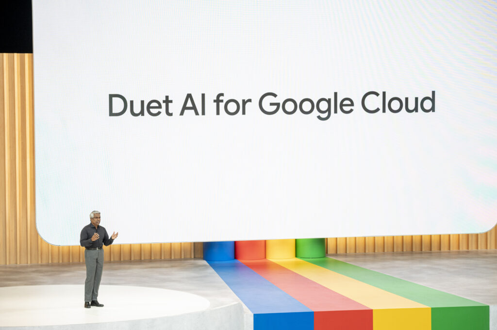 Thomas Kurian steht auf einer großen Bühne. Dahinter Duet AI for Google Cloud aufgebeamt