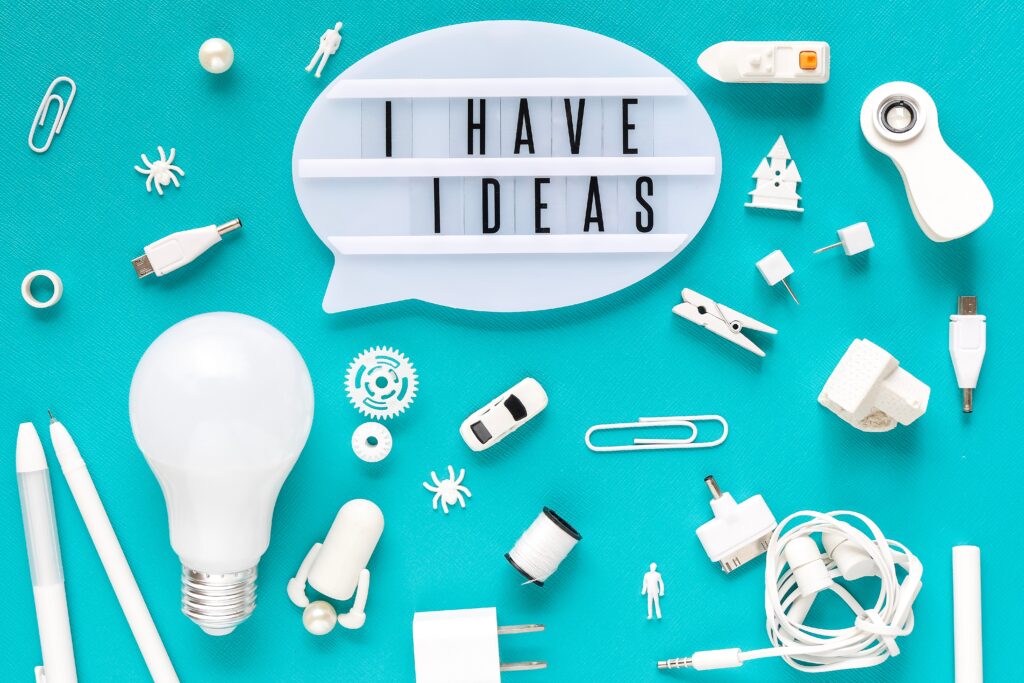 Sprechblase mit I have Ideas und zahlreichen Utensilien wie Wäschekluppe, Büroklammer, kleines Auto, Schiff rumliegen