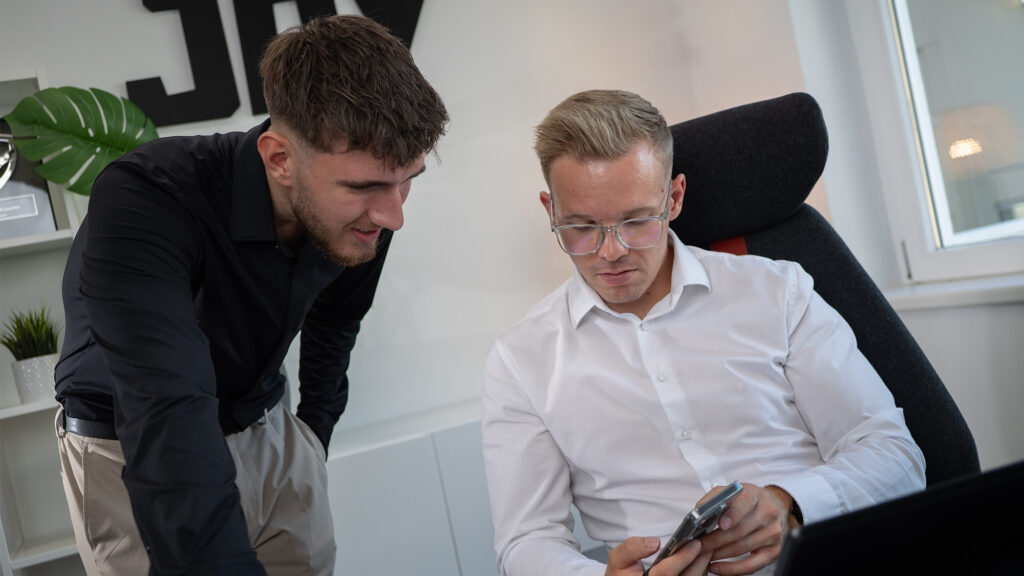 Zwei Männer am Arbeitsplatz schauen auf Handy