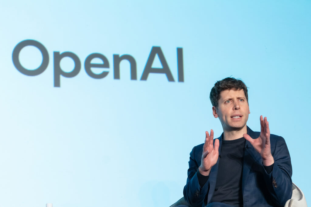 Sam Altman vor dem Open AI Logo